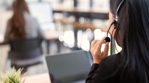 Customer support specialist wearing a headset assisting clients via laptop in a modern office, representing credit management technology and digital financial services support.