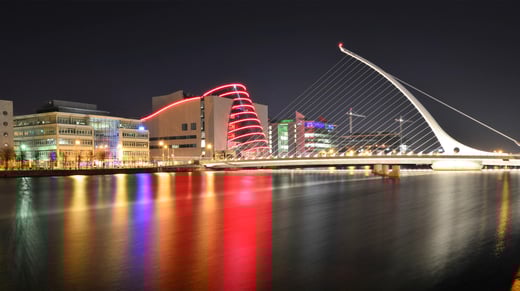 Night photo of Samuel Beckett bridge in Dublin beautifully illuminated by the light of nearby buildings and lanterns
