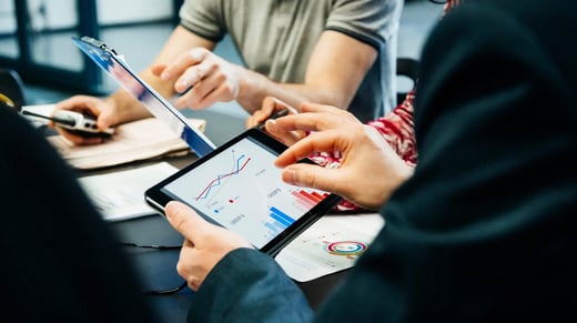 Team of business people reviewing analytics on a tablet and chart.
