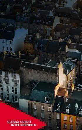 Aerial view of a residential area in the UK in the late afternoon. Global Credit Intelligence chevron point overlaid on bottom left hand corner.