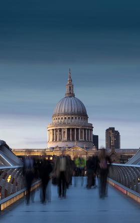 Long exposure shot of Millennium Bridge and St Paul's Cathedral at night. Commuters head home across the River Thames
