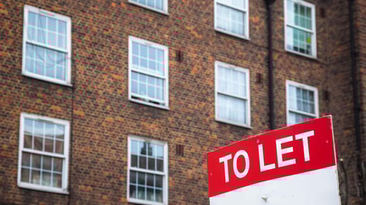 To let sign in front of a dark brown and orange brick building.